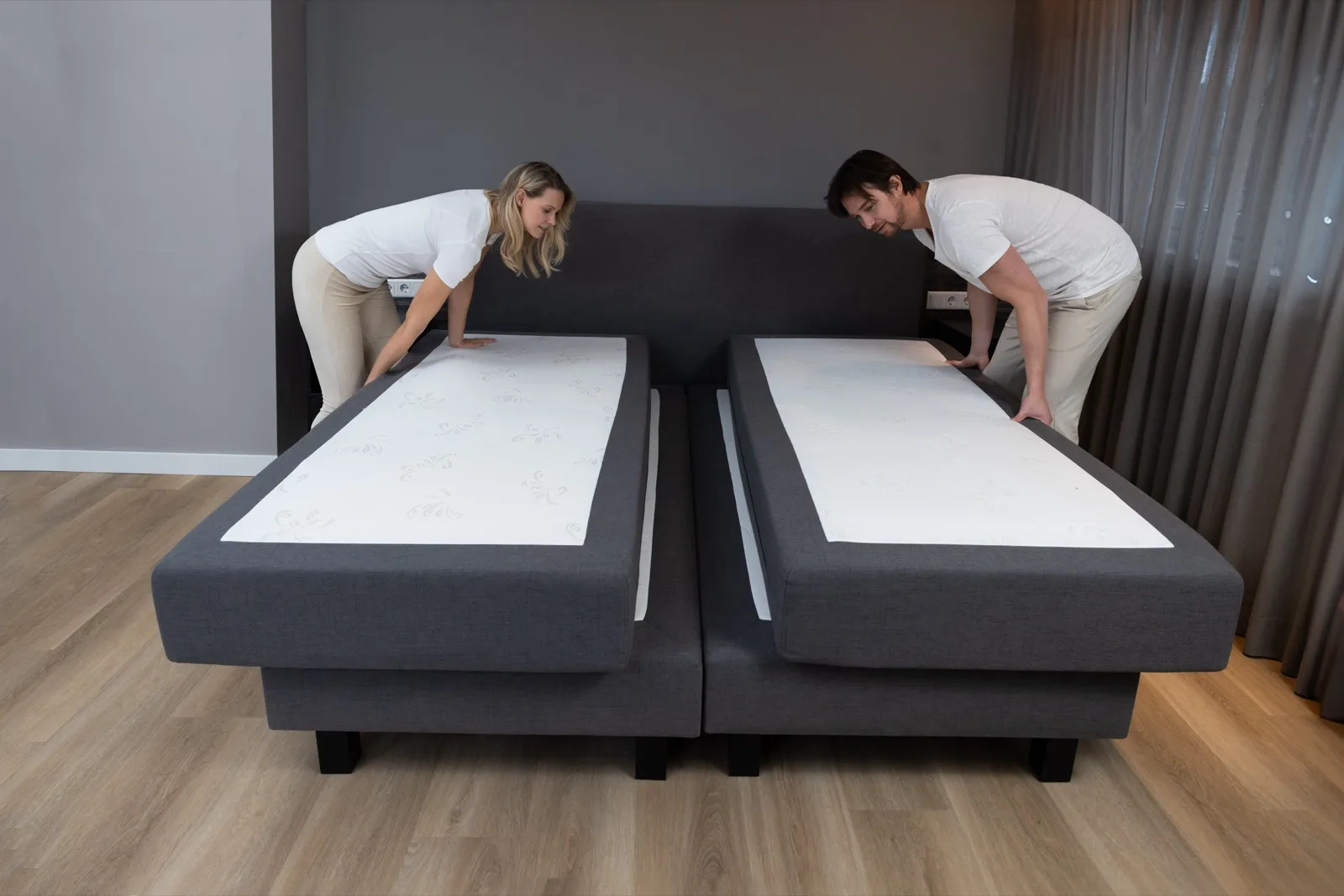 Couple pushing their sliding mattresses back together on a boxspring bed
