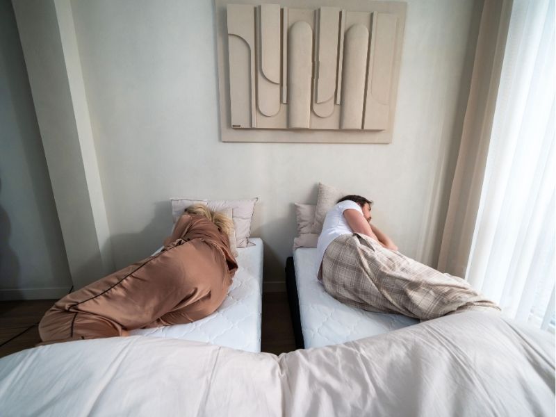 Couple sleeping apart with a visible gap between their mattresses