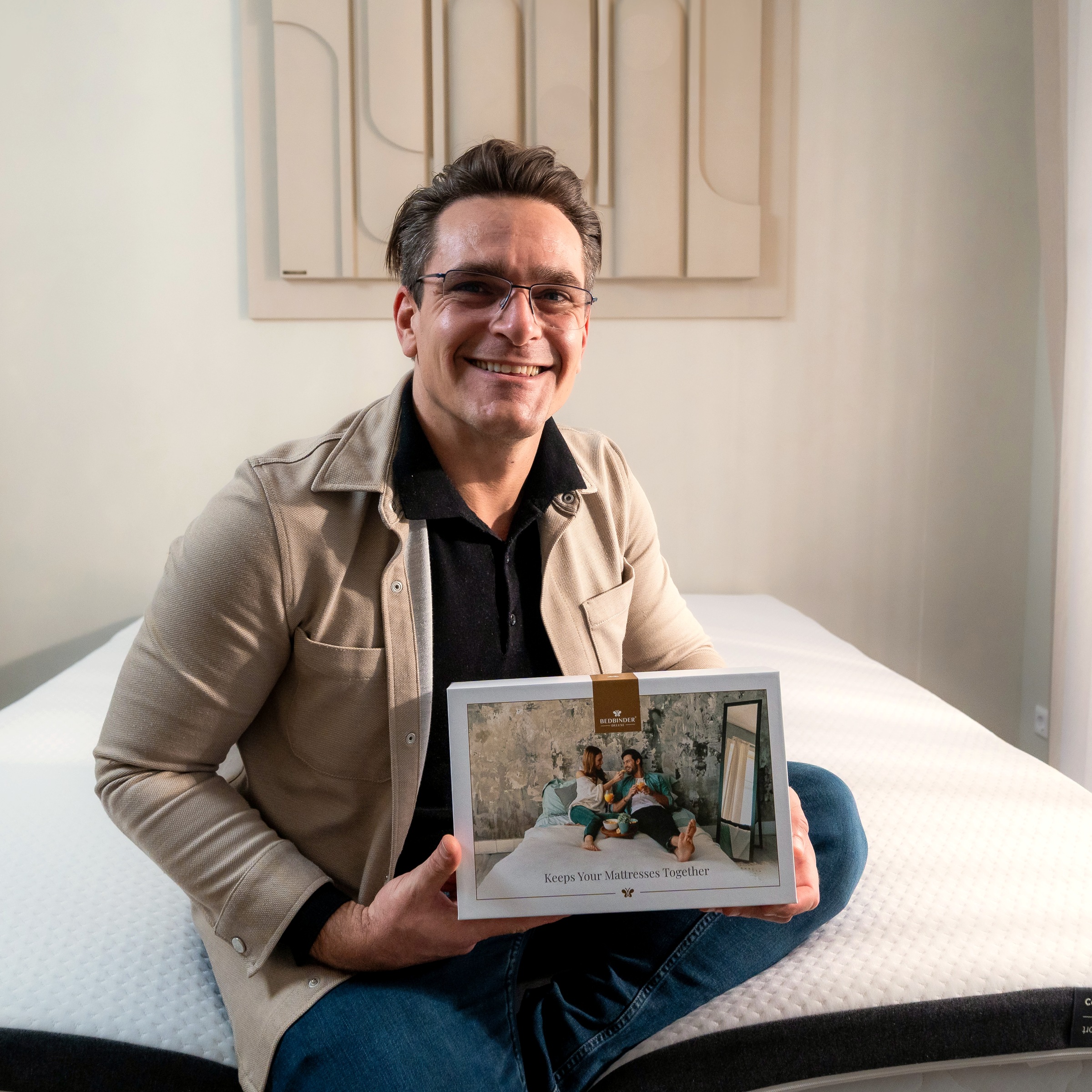 Daniël sentado en una cama con la caja del Bedbinder Deluxe