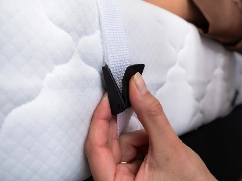 Close-up van een hand die de gesp van de Bedbinder Deluxe vastklikt