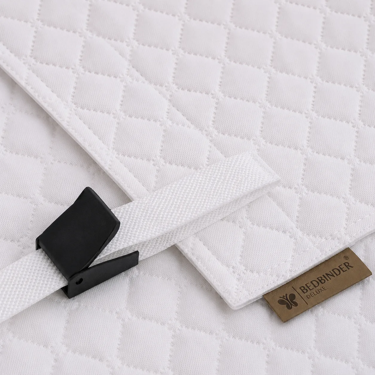 Close-up van de gequilte band, nylon gesp en het Bedbinder Deluxe-merklabel op een matras