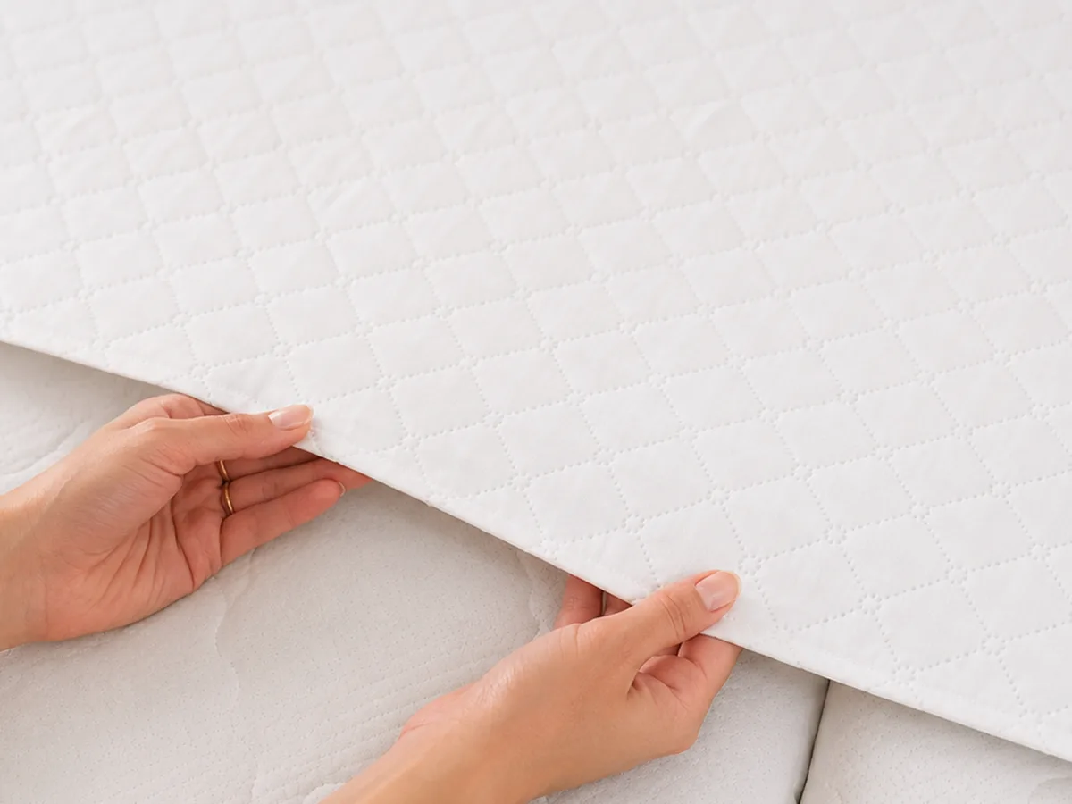 Handen tonen hoe dun het gequilte materiaal van de Bedbinder Deluxe is